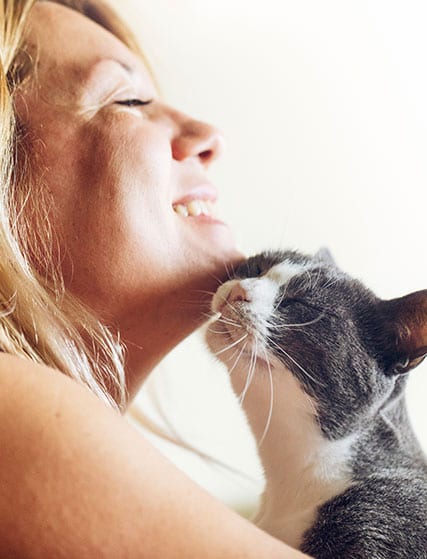 woman snuggling with cat after pet vaccinations
